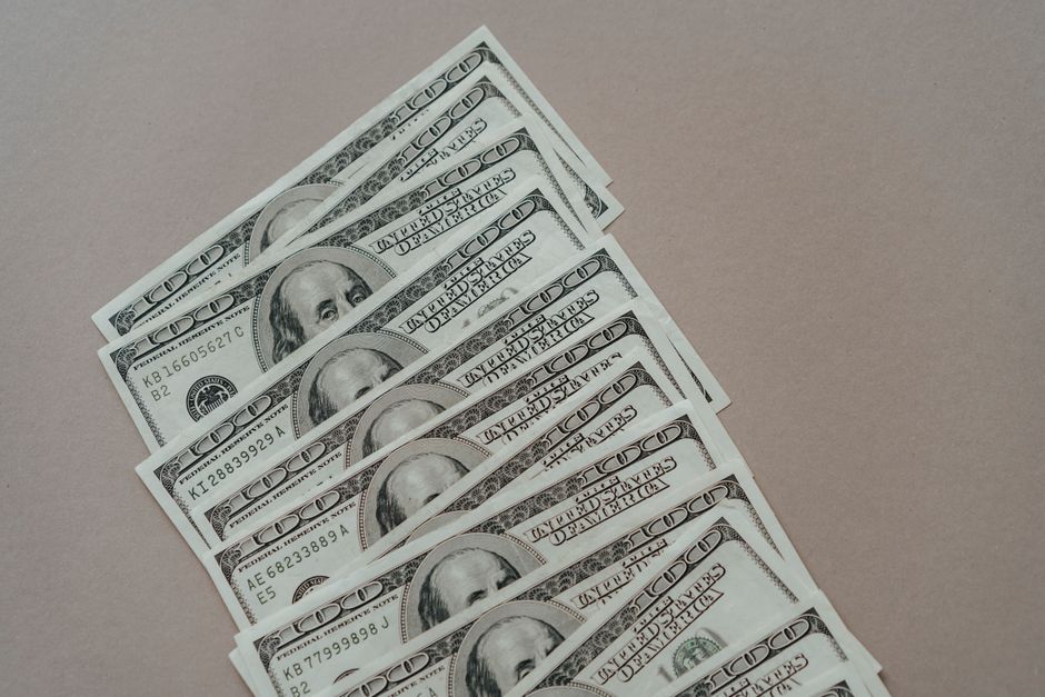 A close-up of multiple US dollar bills arranged on a neutral surface.