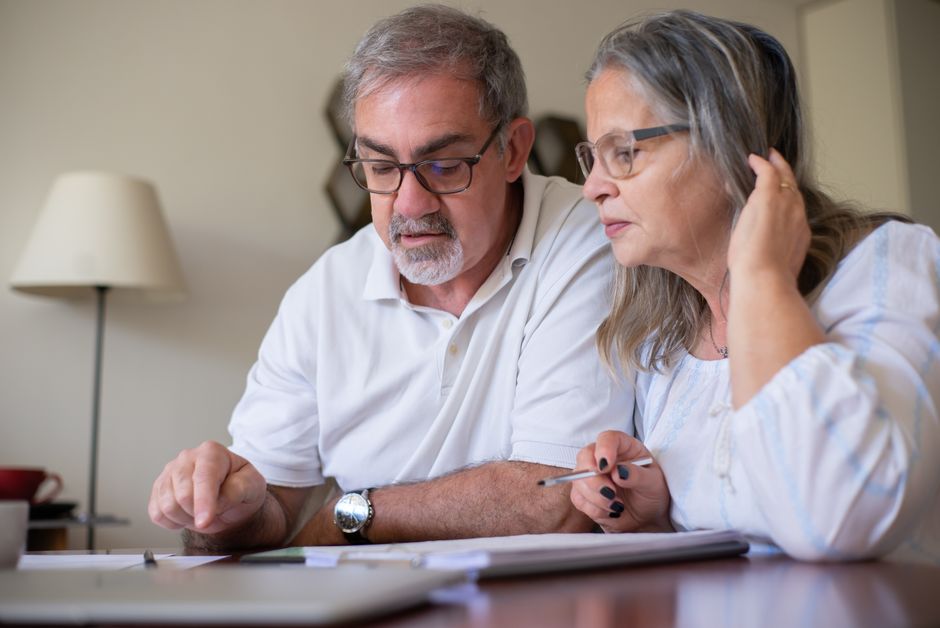 Elderly couple enjoying leisure time with crosswords at home, showcasing togetherness.