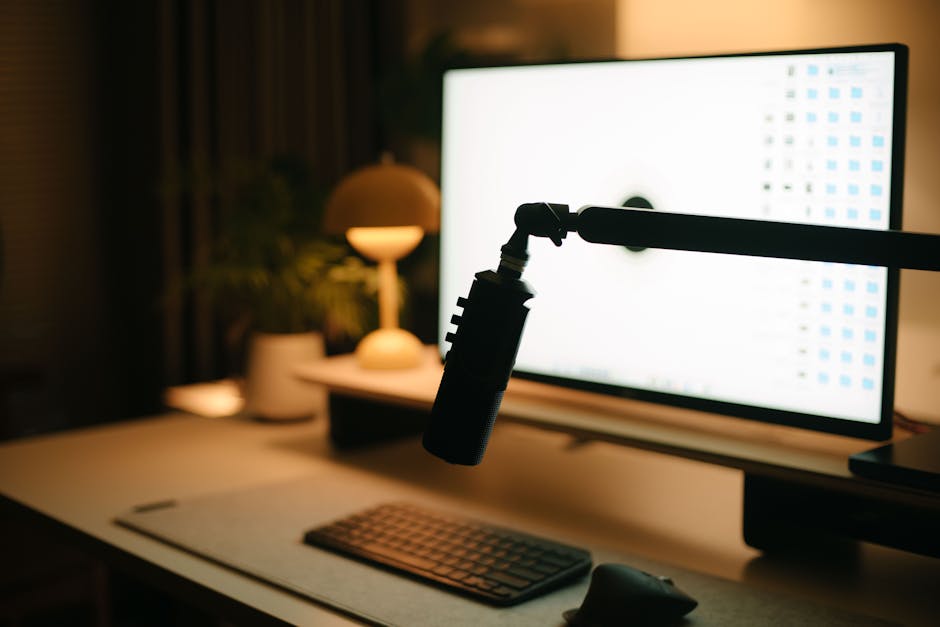 A warm and inviting workspace featuring a computer, microphone, and ambient lighting.