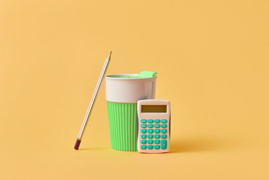 Minimalist desk setup with a pencil, green cup, and calculator on yellow background.