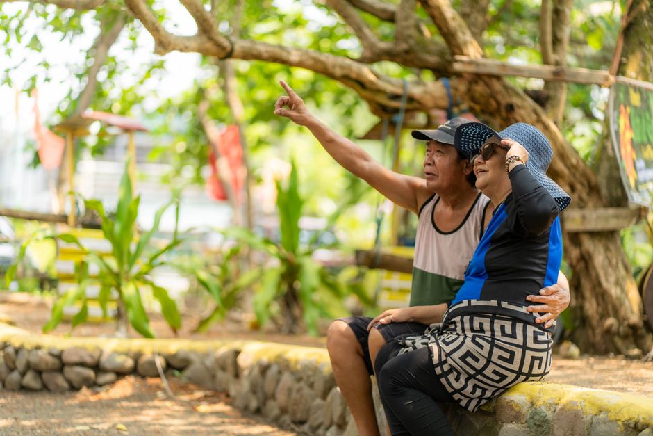 Elderly couple enjoying a sunny day in a park in Quezon, Calabarzon, Philippines, showcasing happy retirement.