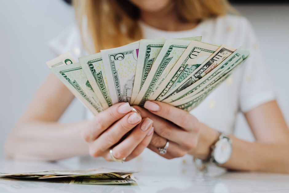 Close-up of a woman counting US dollar bills, symbolizing financial success and wealth man