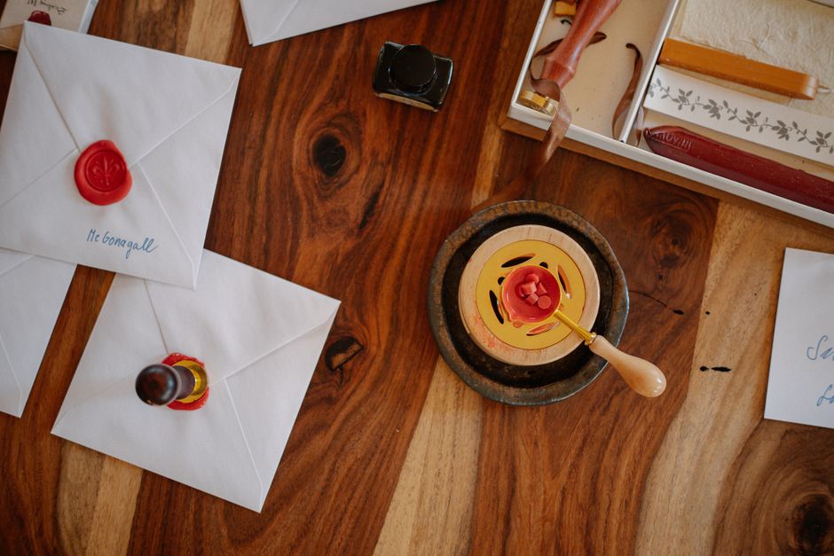 Flat lay of vintage style envelopes with wax seals, stationery, and sealing tools on a wooden surface.