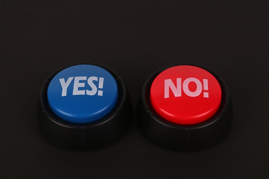 Side-by-side colorful yes and no push buttons on a dark surface symbolize decision making and choices.