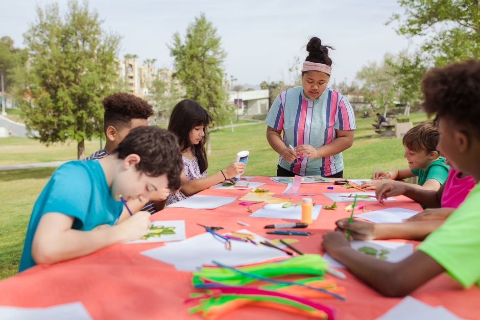 Group of children enjoying an art class outdoors, engaging in drawing and crafts at a tabl