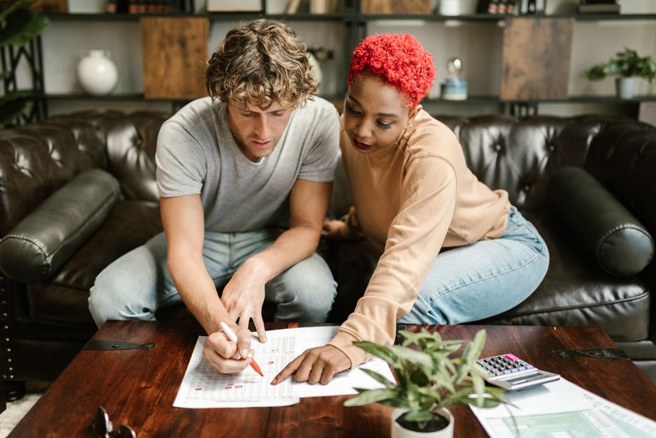 A man and woman collaborating on a project at home, focusing on paperwork.