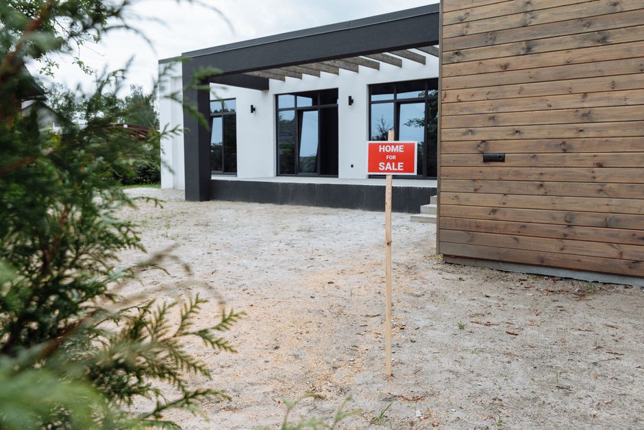 Modern house exterior with a 'Home for Sale' sign in front yard.