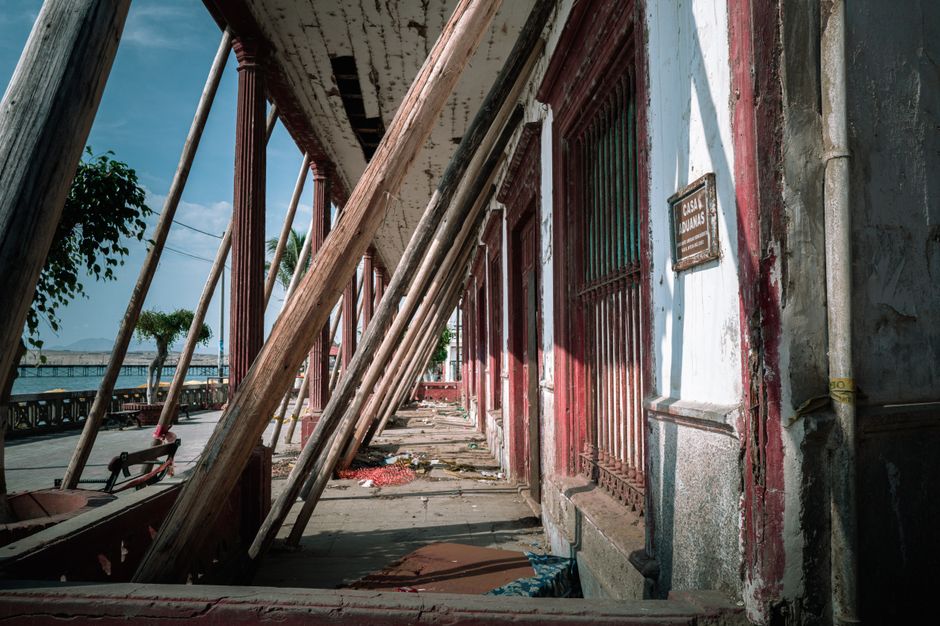 Aged exterior of Casa Aduanas in Pacasmayo, Peru, supported by wooden beams.