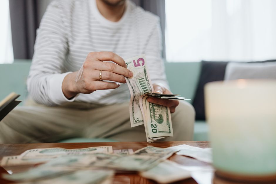 Close-up of hands counting dollar bills indoors, offering a personal finance theme.