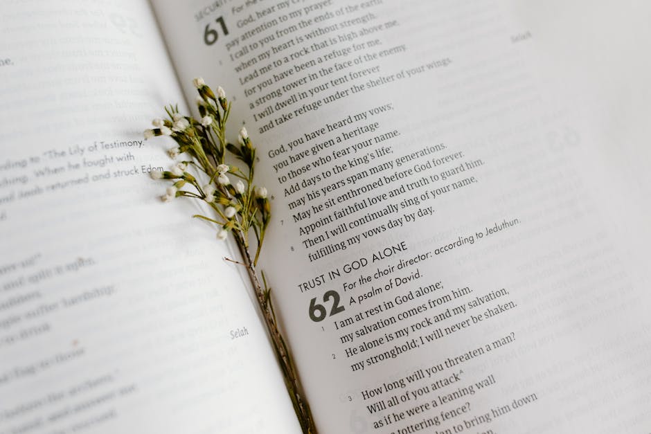 A close-up of an open Bible page with scripture and delicate white flowers.