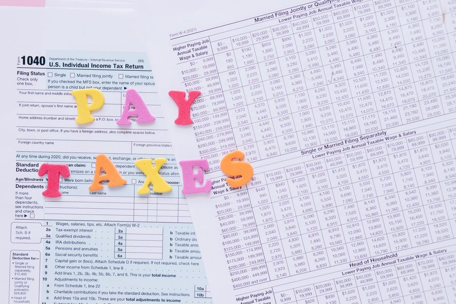Close-up of U.S. tax forms with colorful 'PAY TAXES' letters emphasizing financial deadlines.